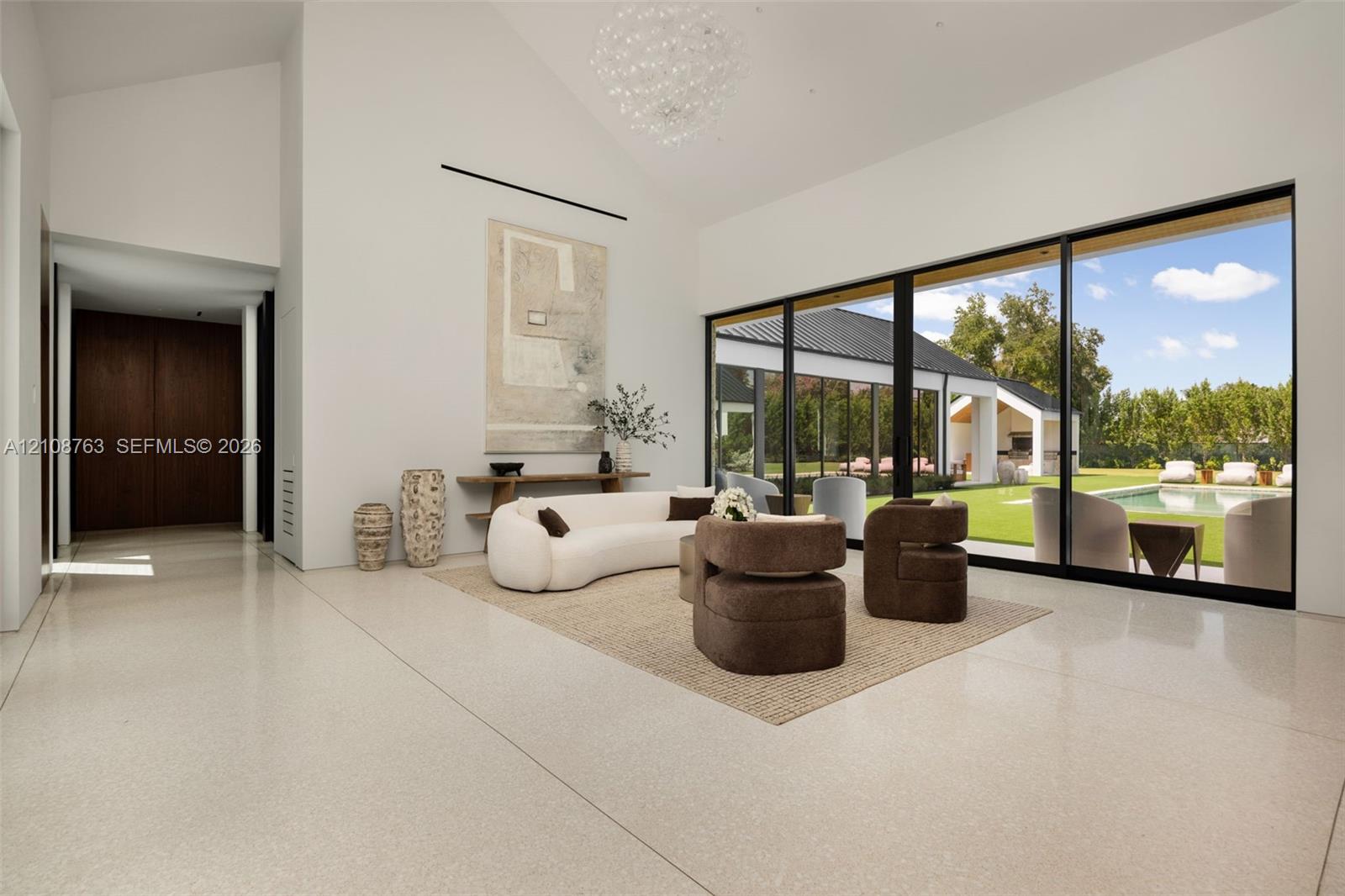 Vaulted ceilings with a contemporary chandelier, expansive multi-panel sliding glass doors, polished stone flooring, and built-in dark wood cabinetry