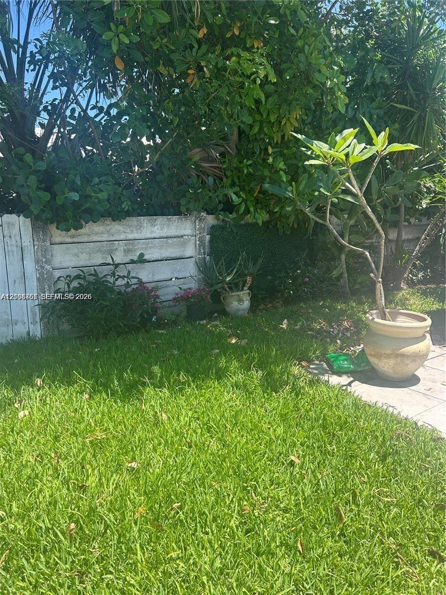 Private outdoor area featuring a manicured lawn, concrete wall perimeter, and mature landscape