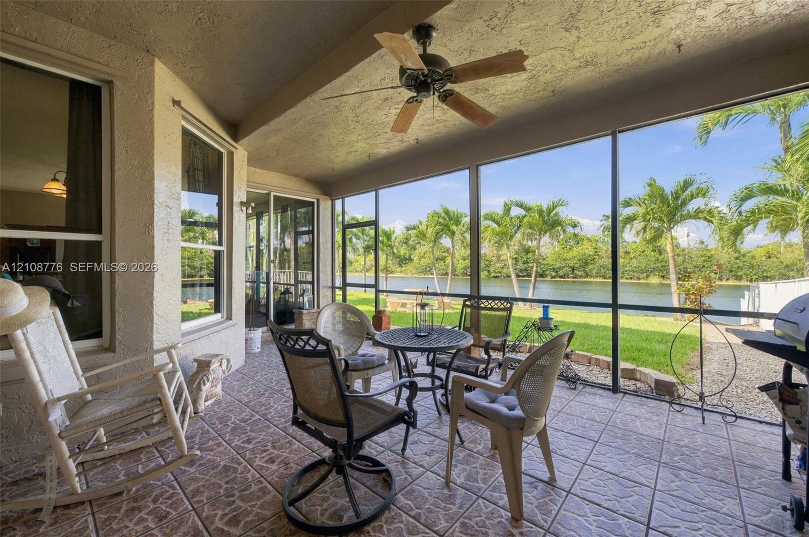 Screened-in lanai featuring tiled flooring, a ceiling fan, and metal framing