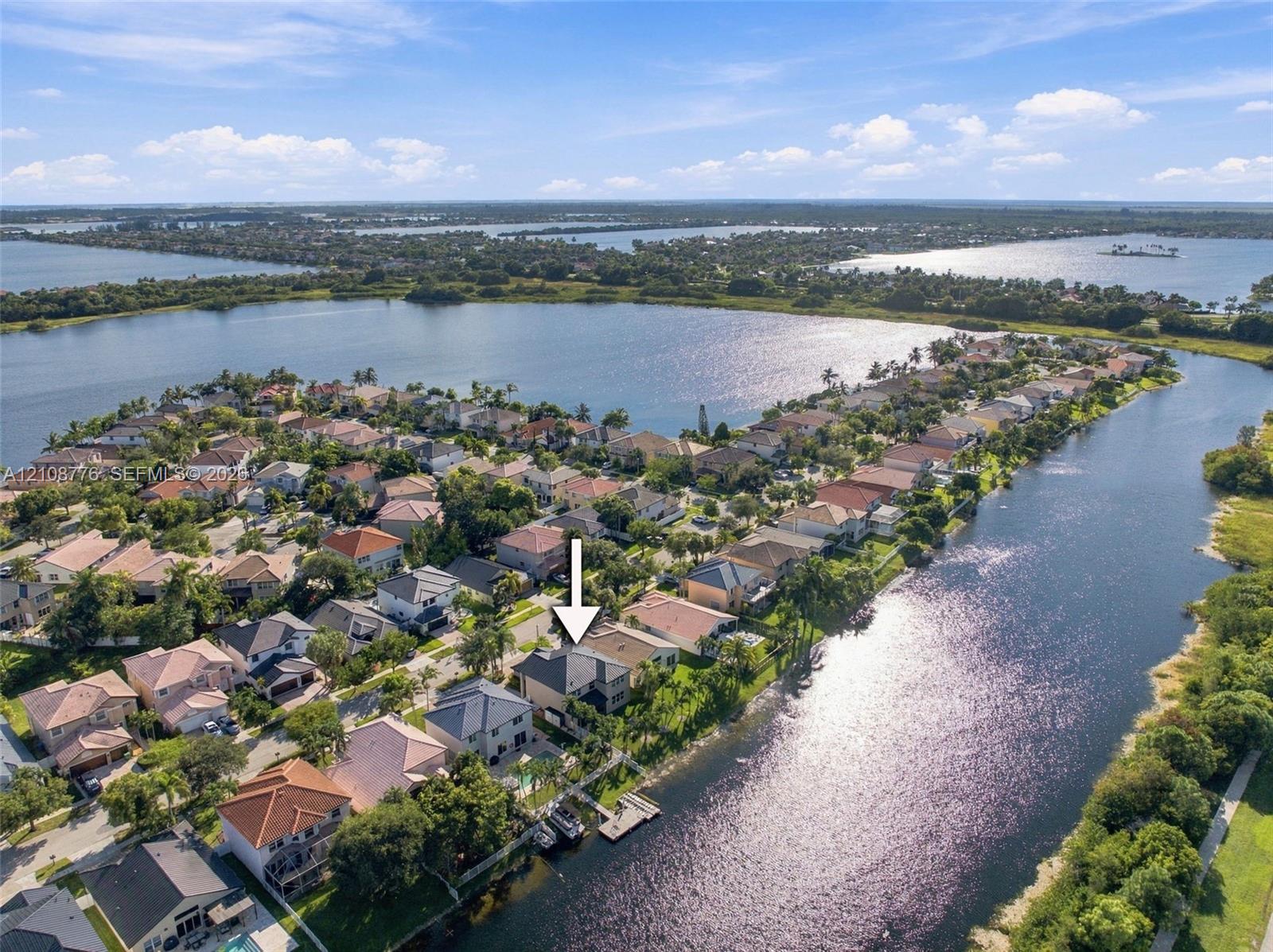 Aerial perspective of a waterfront residential property featuring a private boat dock and tile roofing