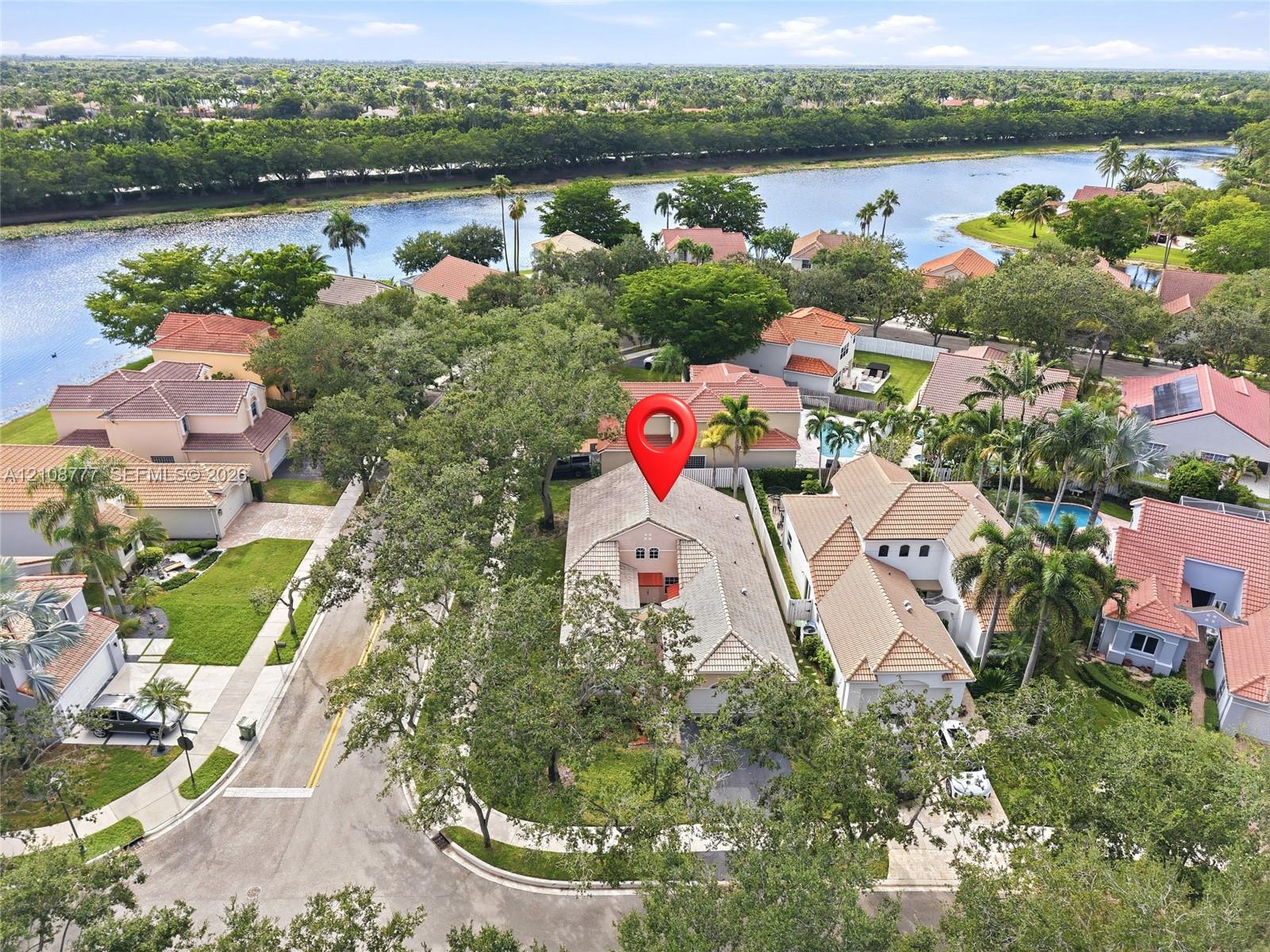 Aerial perspective featuring a multi-story residence with a pitched tile roof, positioned on a corner lot within a waterfront community