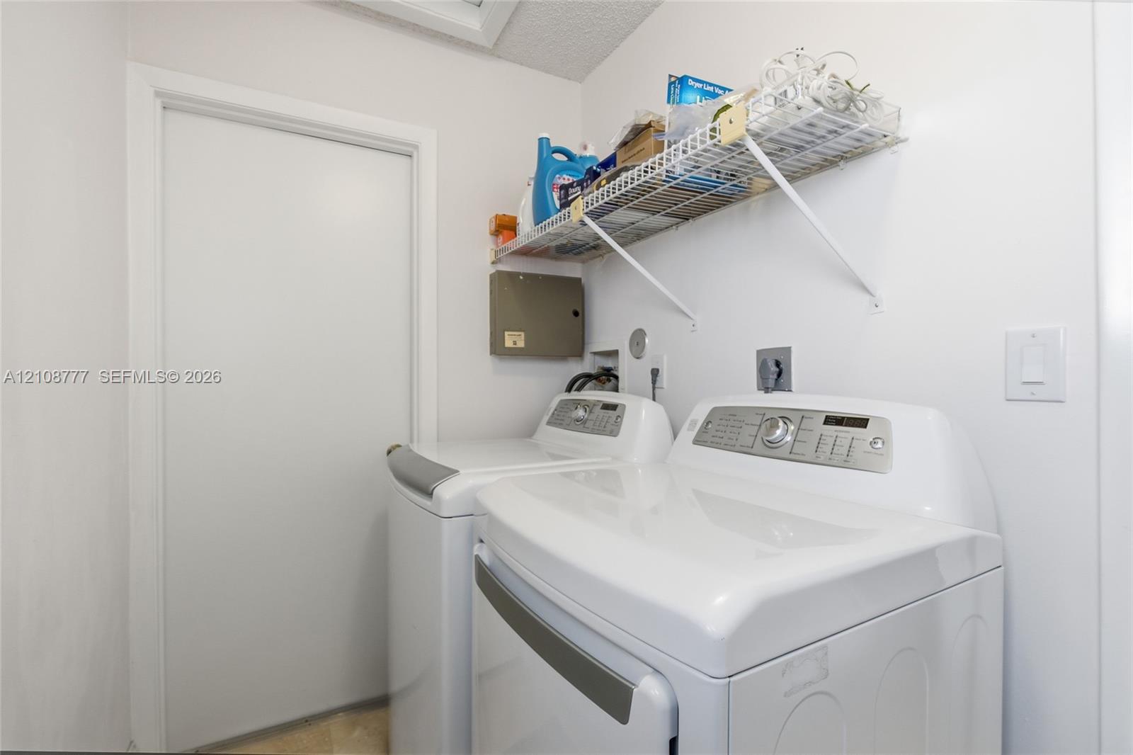 Laundry area featuring white appliance hookups and a mounted wire shelving unit