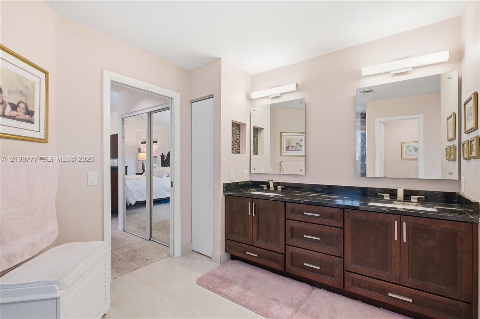 Dual-vanity cabinet with dark-finish wood cabinetry, integrated stone countertops, dual under-mount sinks, and wall-mounted linear light fixtures