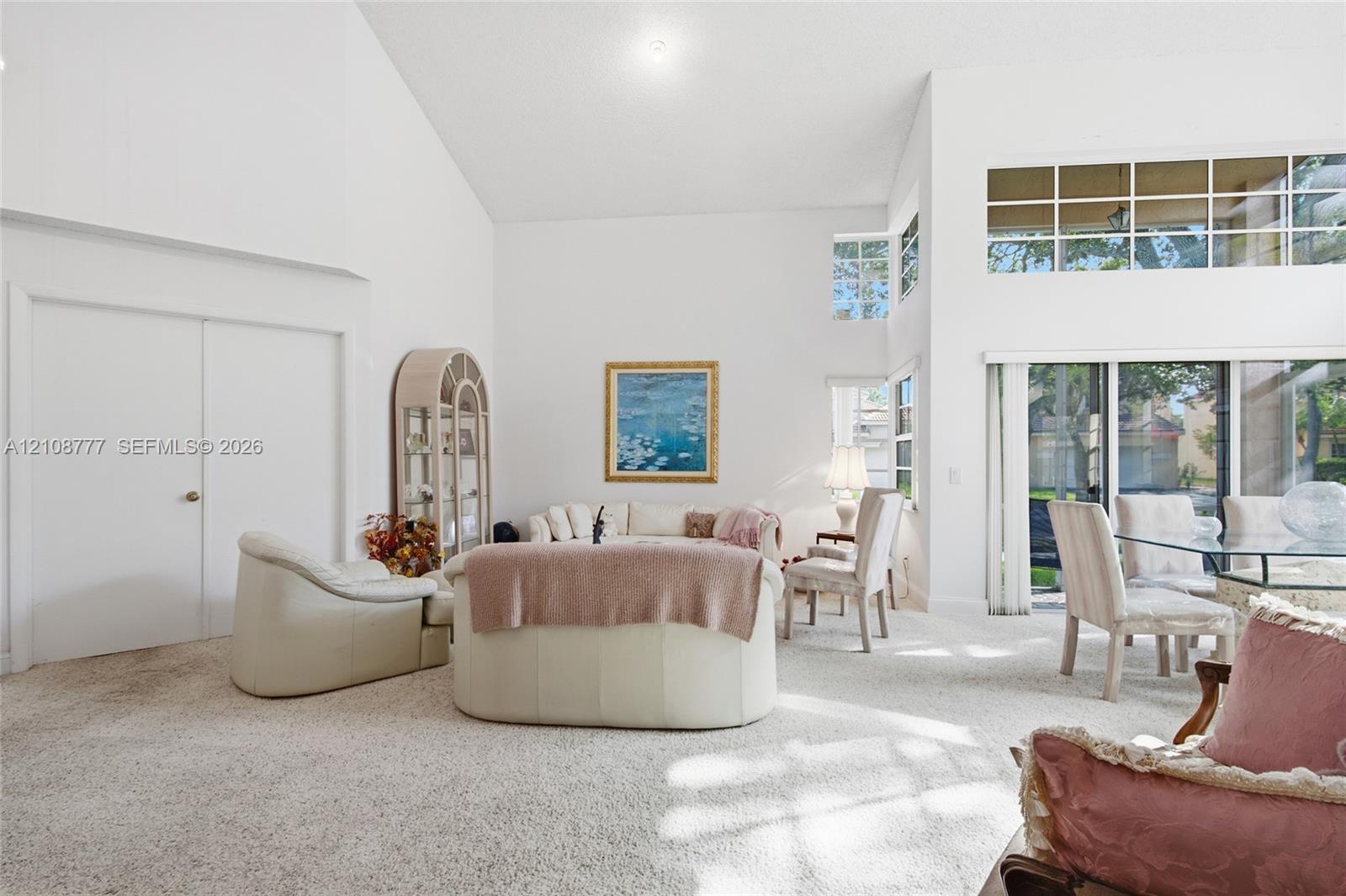 High vaulted ceilings featuring clerestory windows, sliding glass doors, and a neutral color palette
