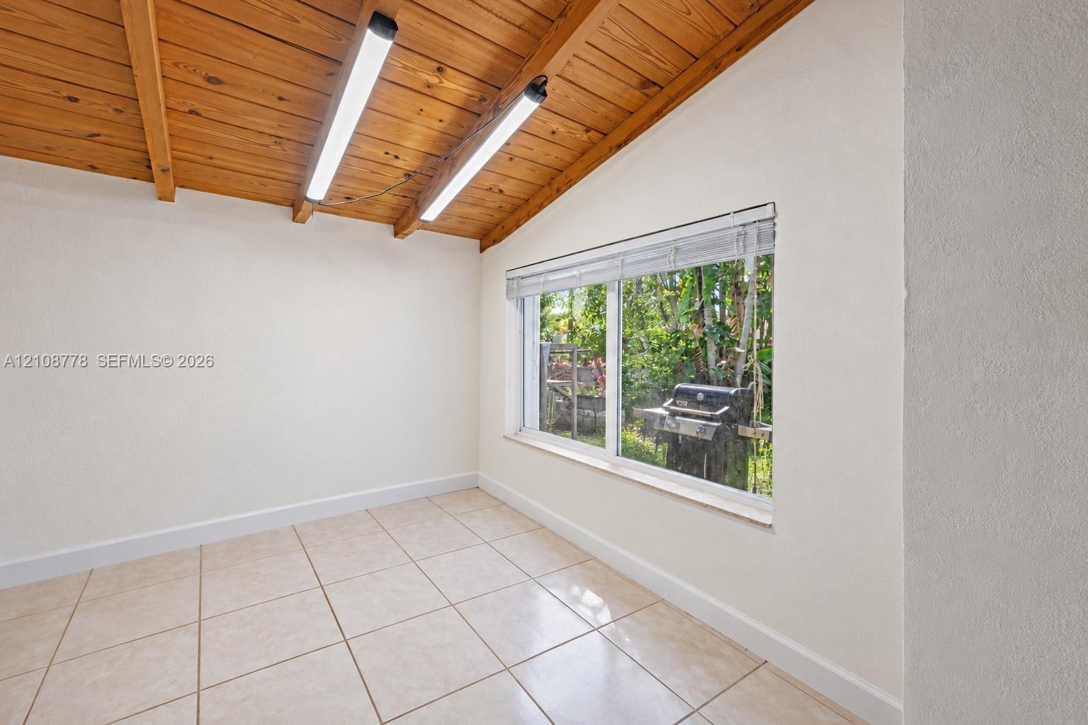 Exposed wood-plank beamed ceiling, ceramic tile flooring, and a large horizontal window with integrated blinds