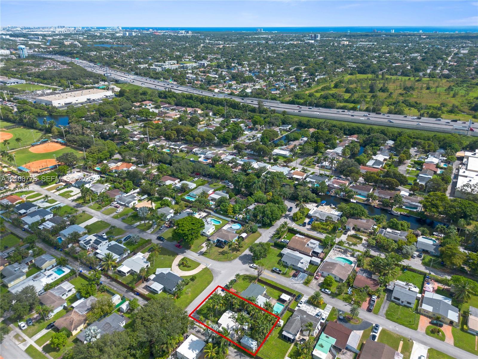 Aerial perspective of a corner lot property featuring mature landscaping and a perimeter boundary line