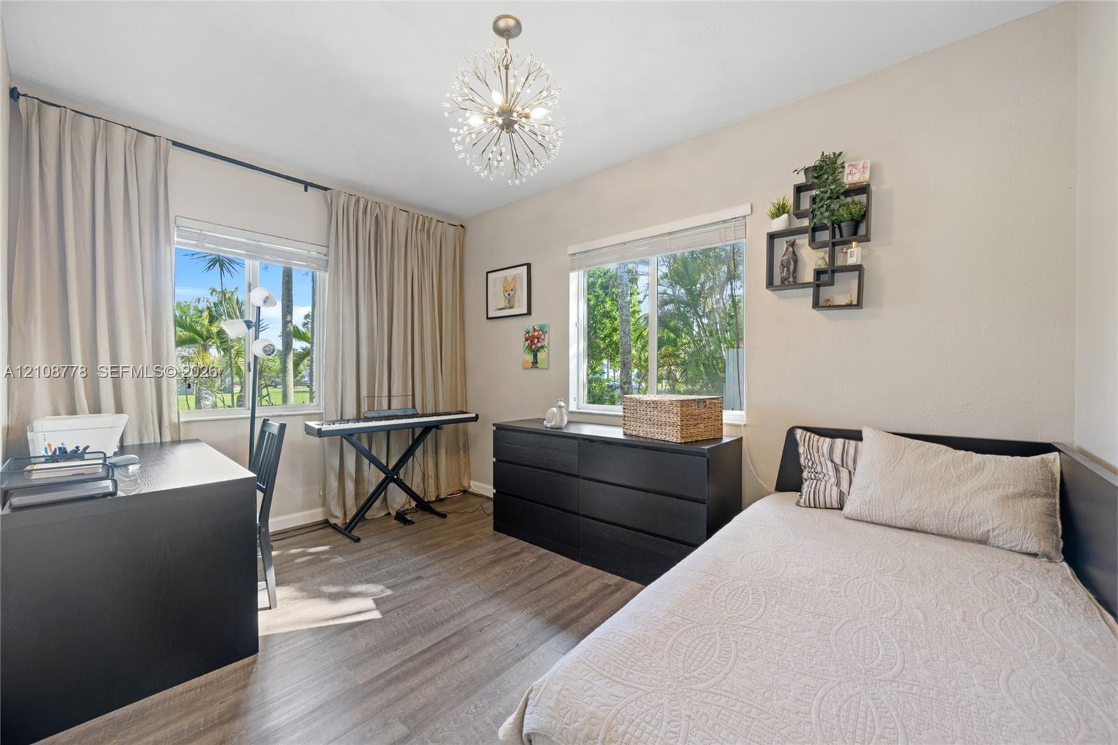 Wood-finish flooring, dual windows with exterior palm tree scenery, and a contemporary multi-arm spherical ceiling fixture