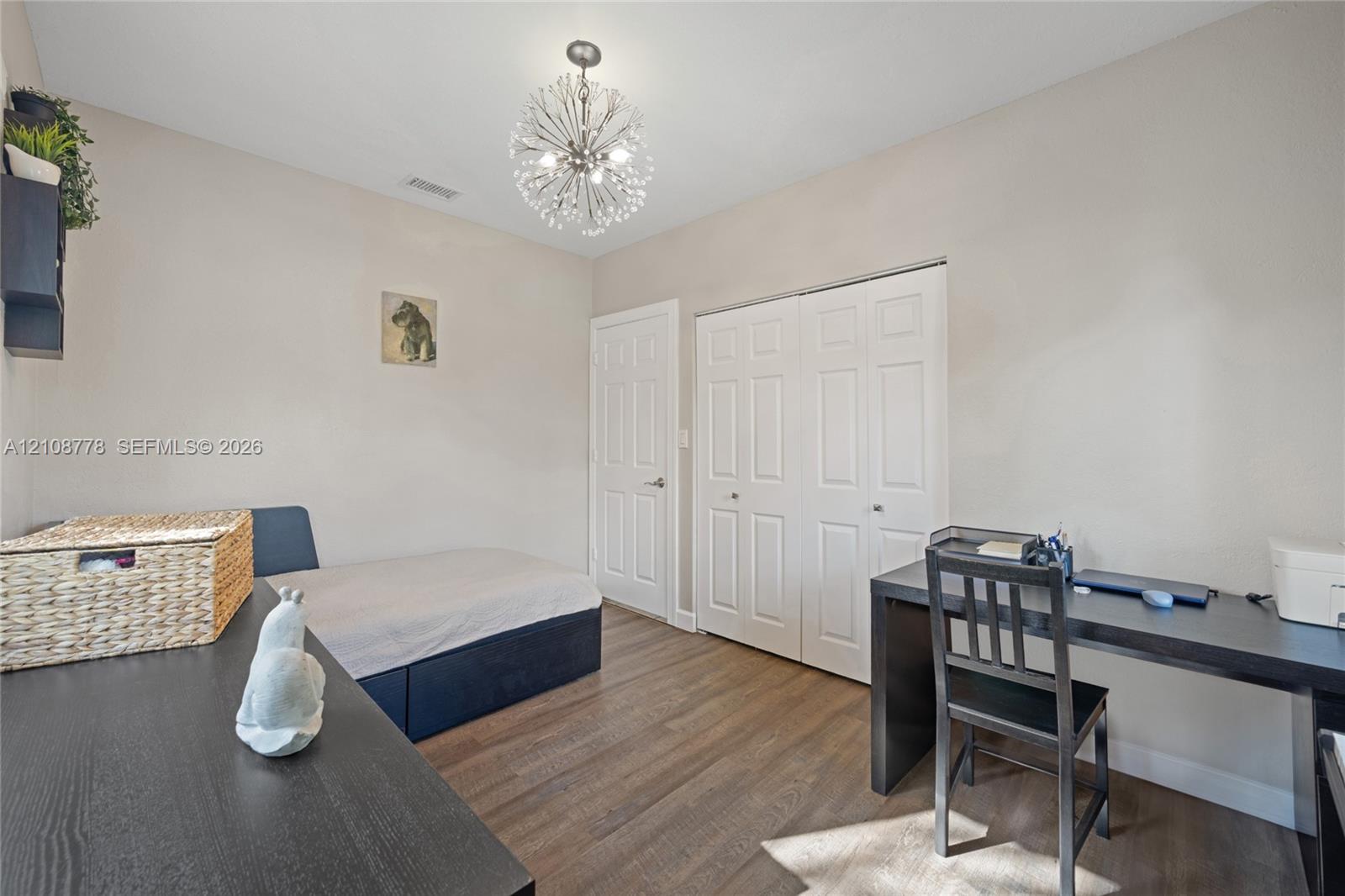Room featuring wood-finish flooring, a contemporary starburst chandelier, white paneled interior doors, and a double-door closet