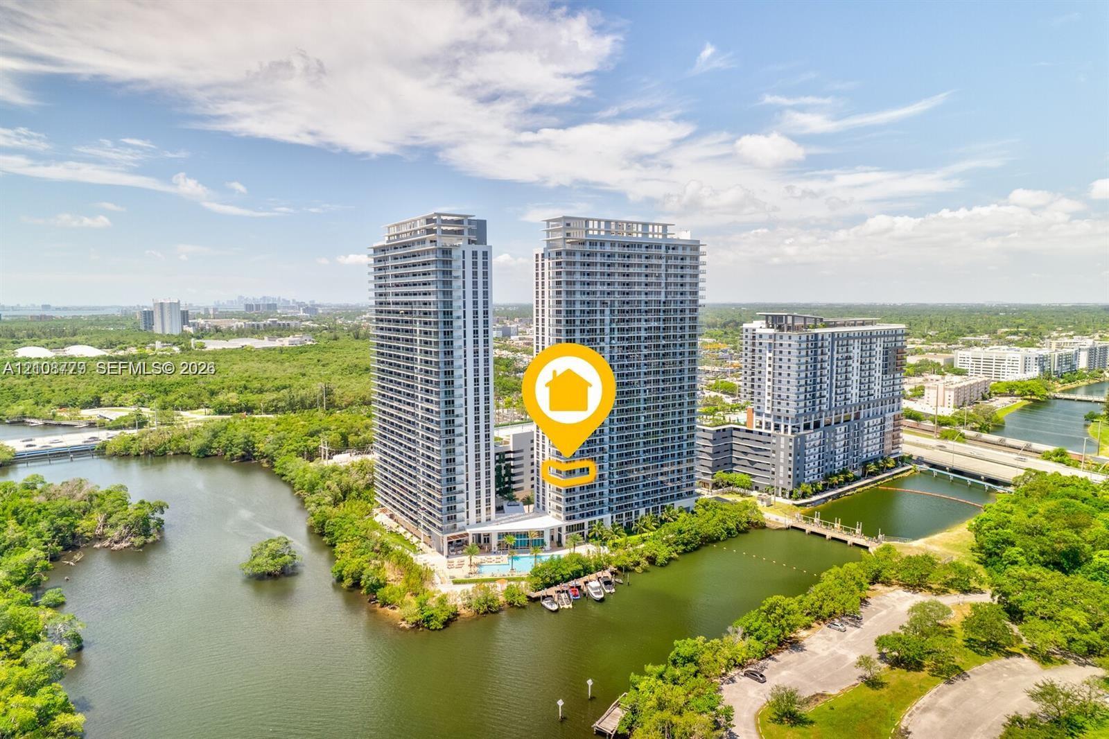 High-rise residential towers featuring glass-paneled balconies and a ground-level swimming pool, situated on a waterfront parcel with a private dock