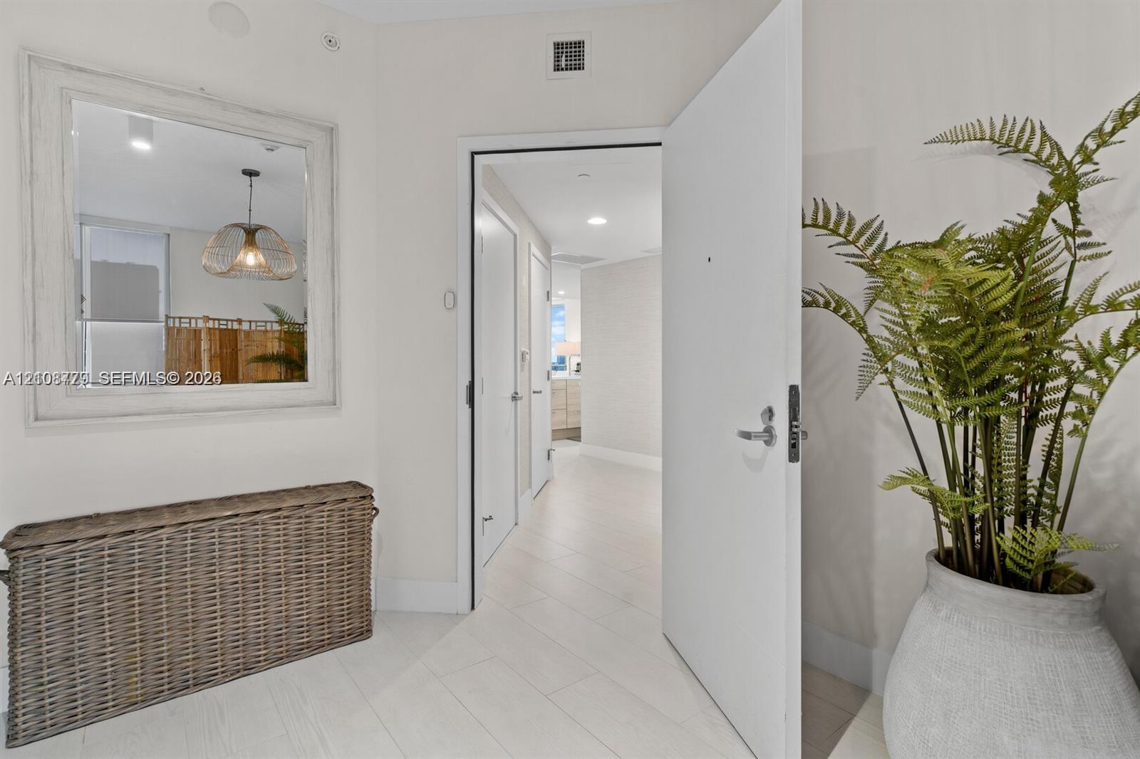Entryway featuring large-format light tile flooring, recessed ceiling lighting, and a wall-mounted rectangular mirror with a white frame