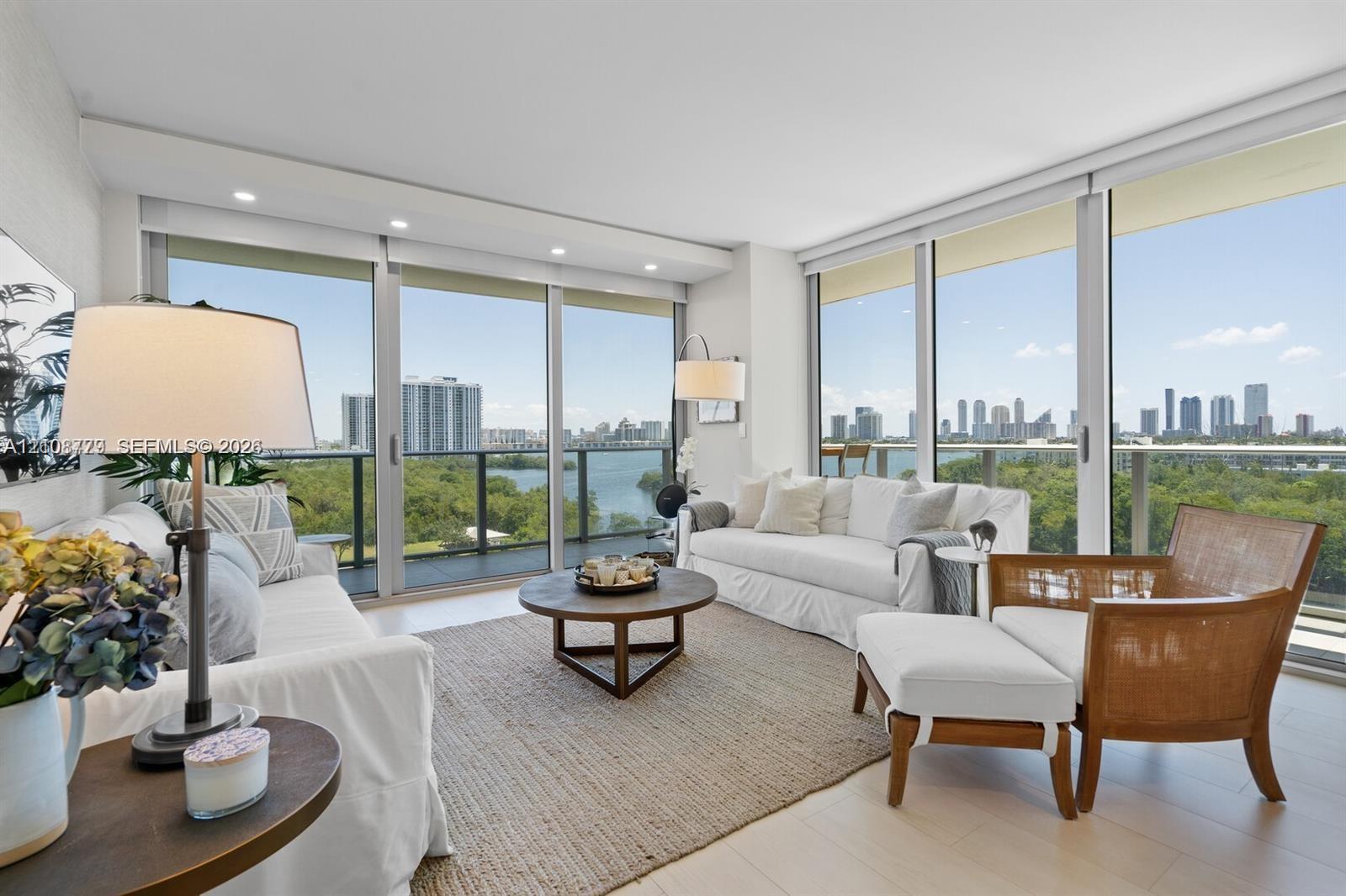 Floor-to-ceiling glass walls, recessed lighting, wood-finish flooring, and a private balcony featuring a metal railing