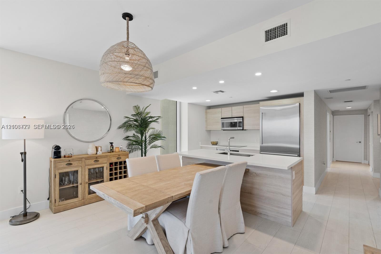 Open-concept kitchen featuring light wood-finish cabinetry, quartz countertops, stainless steel appliances, recessed lighting, and large-format flooring Open-concept kitchen featuring light wood-finish cabinetry, quartz countertops, stainless steel appliances, recessed lighting, and large-format flooring
