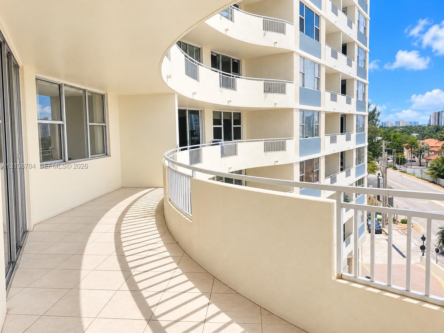 Curved exterior balcony featuring tiled flooring and metal railings