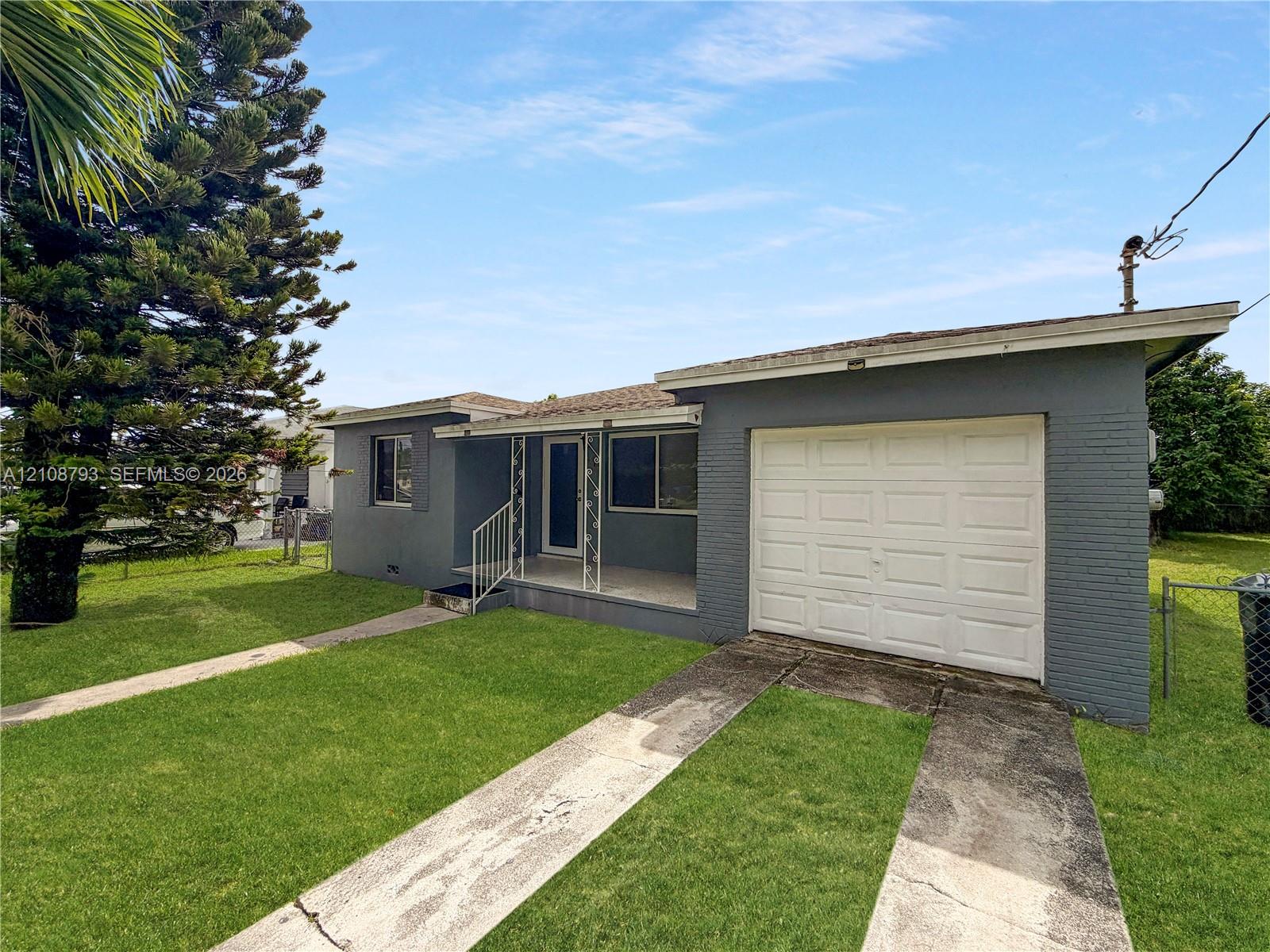 Single-story exterior featuring painted masonry siding, a covered front porch with decorative metal railing, and an attached one-car garage Single-story exterior featuring painted masonry siding, a covered front porch with decorative metal railing, and an attached one-car garage