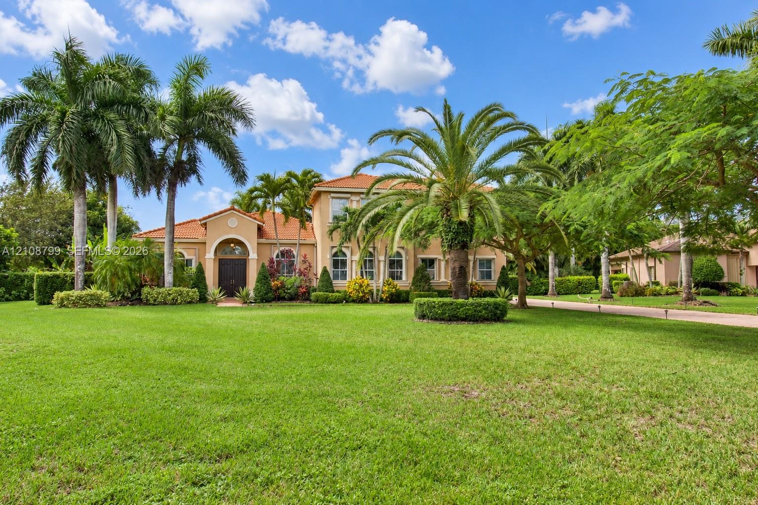 Stucco exterior with an arched entryway, terracotta tile roof, and expansive manicured lawn featuring mature palm trees Stucco exterior with an arched entryway, terracotta tile roof, and expansive manicured lawn featuring mature palm trees