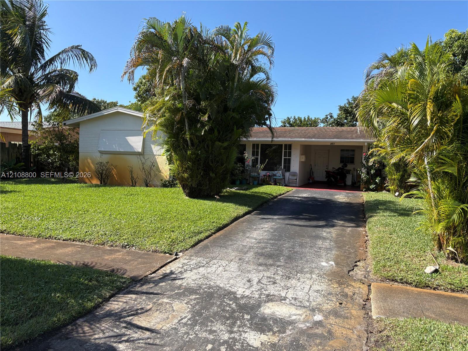 Single-story exterior featuring a covered front entry, asphalt driveway, and mature landscaping