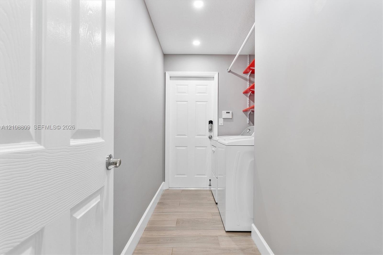 Laundry area featuring wood-finish flooring, recessed lighting, and a six-panel interior door