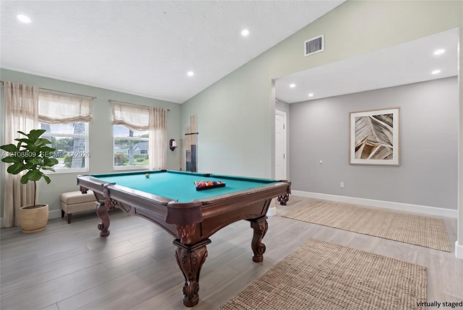 Vaulted ceiling with recessed lighting, wood-finish flooring, and multiple windows