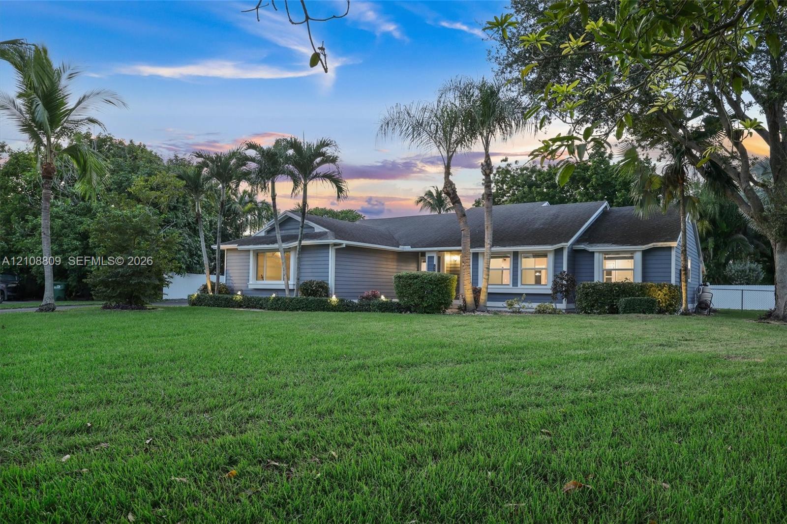 Single-story residence featuring horizontal lap siding, a shingled roof, multi-pane windows, and extensive mature landscaping Single-story residence featuring horizontal lap siding, a shingled roof, multi-pane windows, and extensive mature landscaping