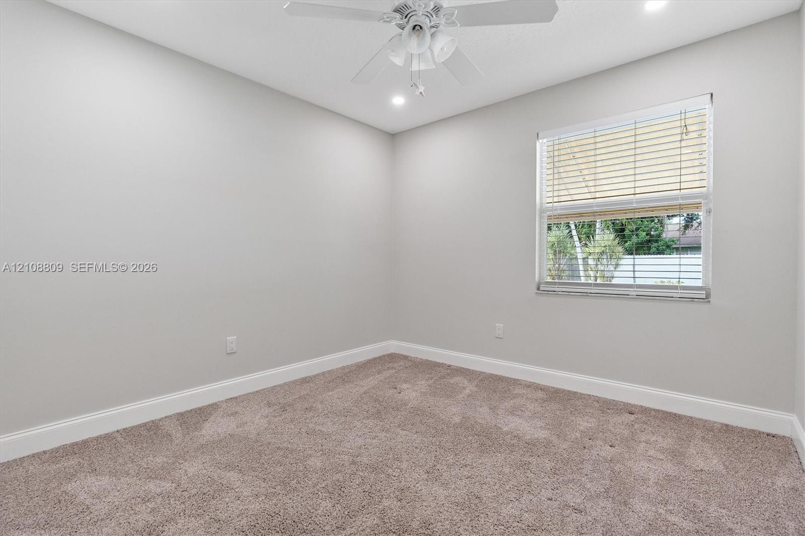 Neutral interior space featuring wall-to-wall carpeting, a ceiling fan with integrated lighting, recessed lighting, and a window with horizontal blinds