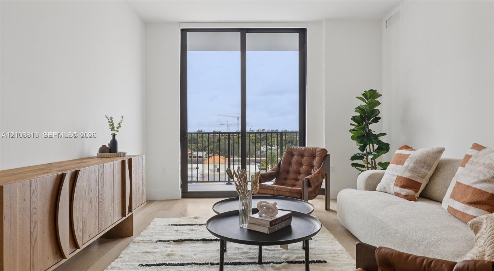 Floor-to-ceiling sliding glass door with a metal frame, wood-finish flooring, and a private exterior balcony