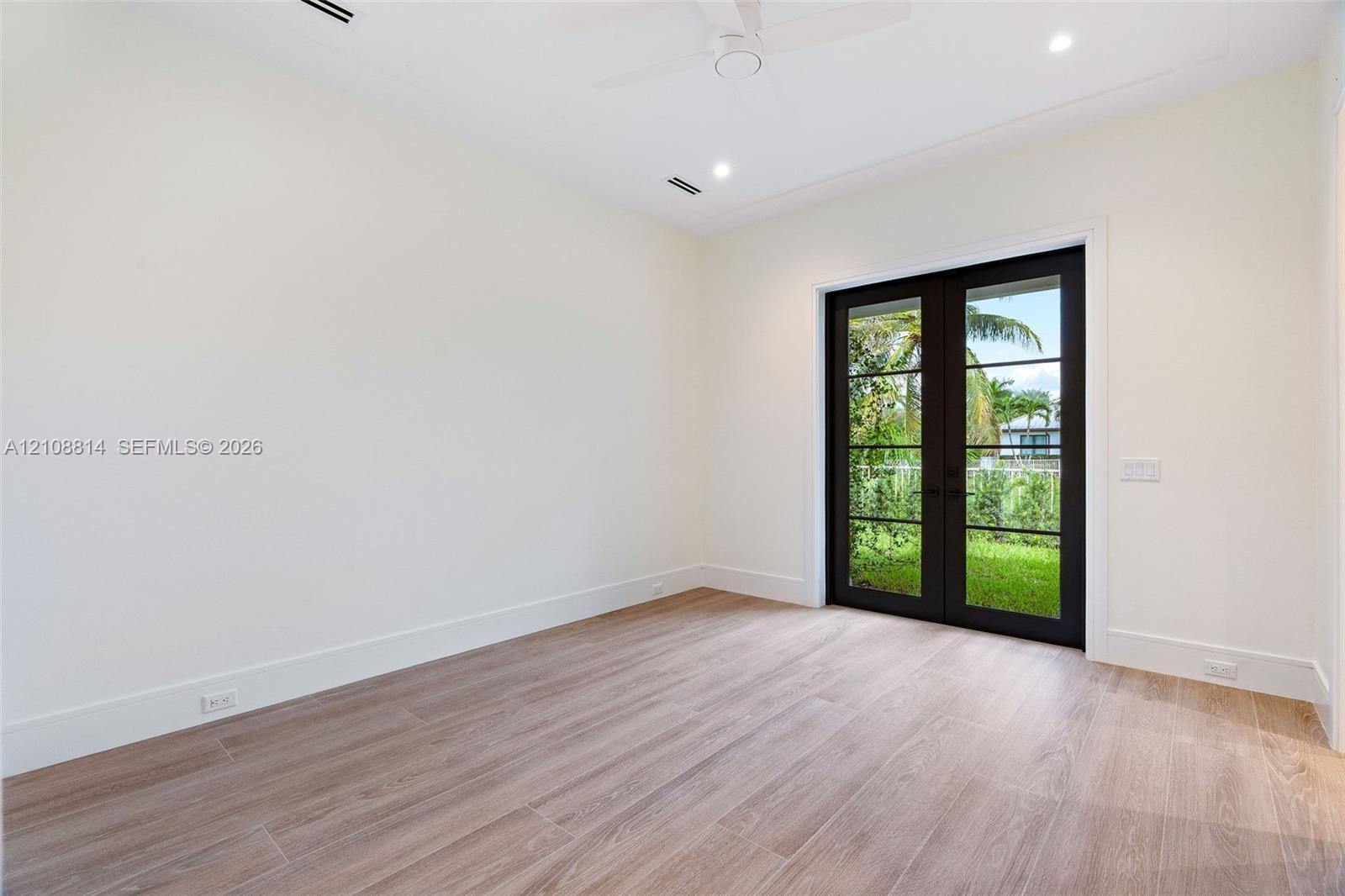 Neutral interior featuring porcelain-finish flooring, recessed lighting, a ceiling fan, and French doors with black frames opening to exterior landscaping