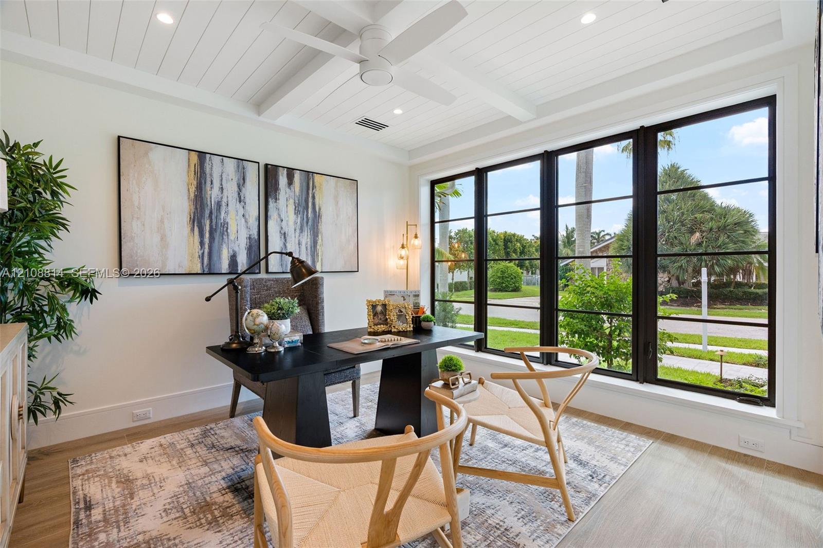 Beamed ceiling with white tongue-and-groove paneling, expansive multi-pane window wall with black frames, porcelain-finish flooring, and integrated recessed lighting