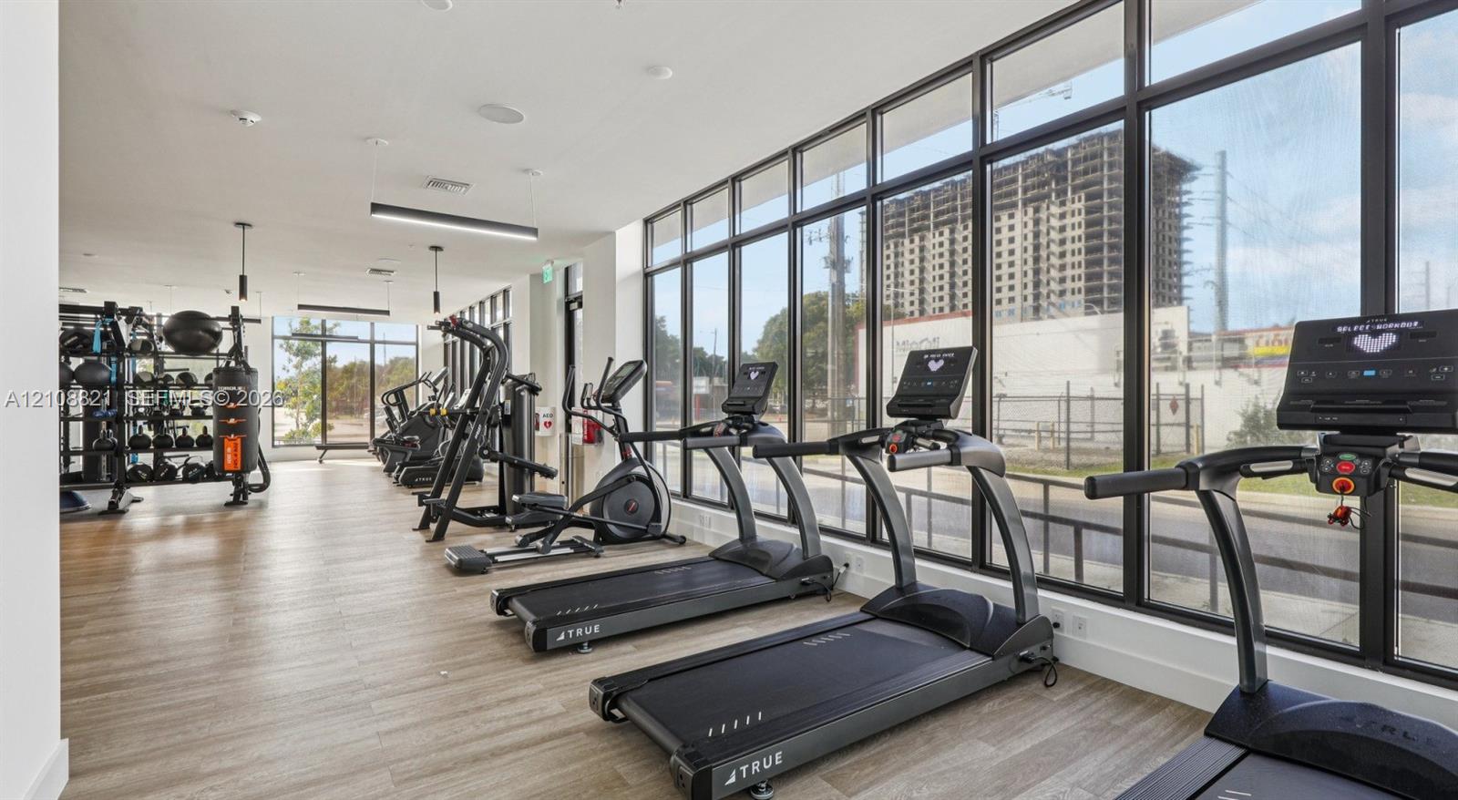 Fitness center featuring floor-to-ceiling windows, wood-finish flooring, and recessed ceiling lighting