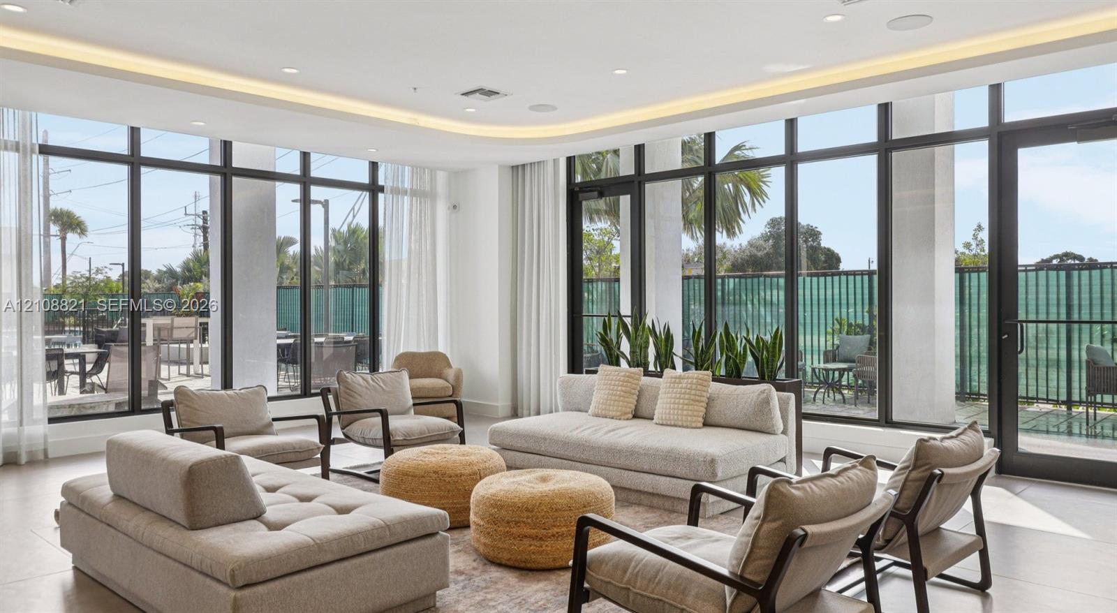 Open-concept space featuring floor-to-ceiling windows, recessed cove lighting, sleek tile flooring, and metal-framed exterior access doors