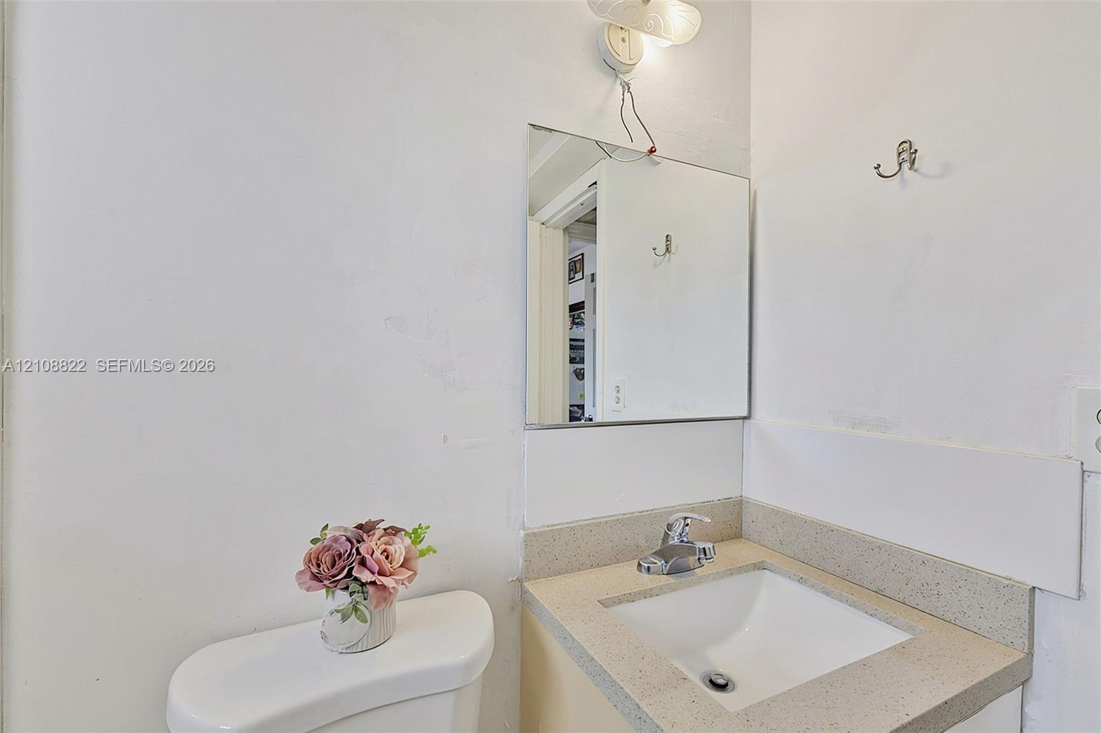 Wall-mounted mirror, vanity with a light-toned countertop, and integrated sink with a polished metal faucet