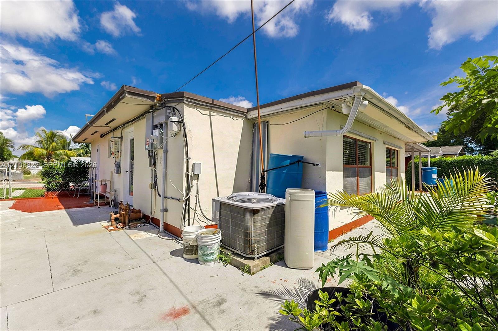 Stucco exterior featuring concrete paved surfaces, window shutters, and central air conditioning unit
