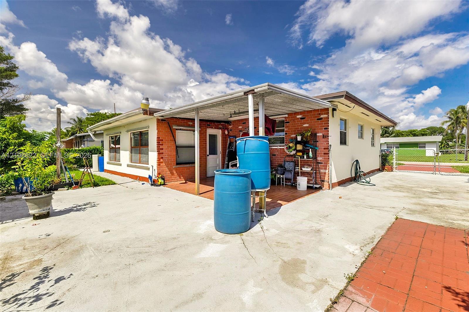 Single-story residence featuring a brick and stucco exterior, covered patio, concrete driveway, and gated perimeter