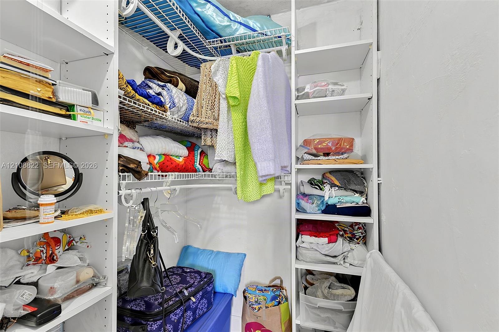 Walk-in closet featuring white built-in shelving and wire garment racks