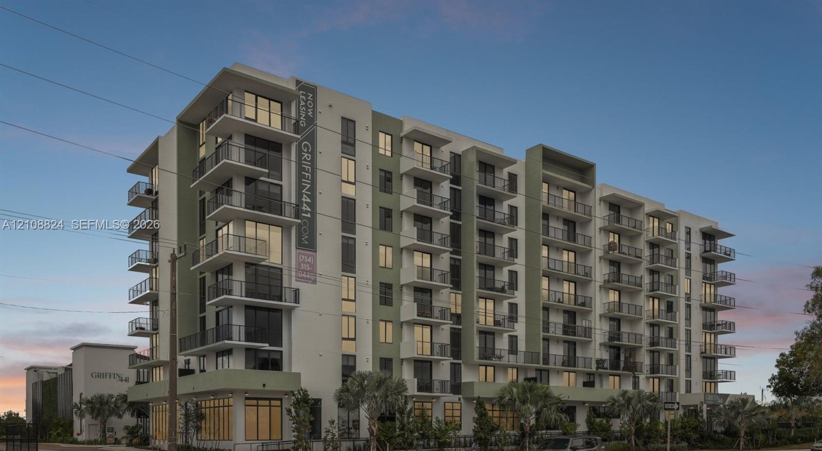 Modern multi-story residential building featuring a concrete exterior facade, expansive floor-to-ceiling glass windows, and private cantilevered balconies with metal railings Modern multi-story residential building featuring a concrete exterior facade, expansive floor-to-ceiling glass windows, and private cantilevered balconies with metal railings