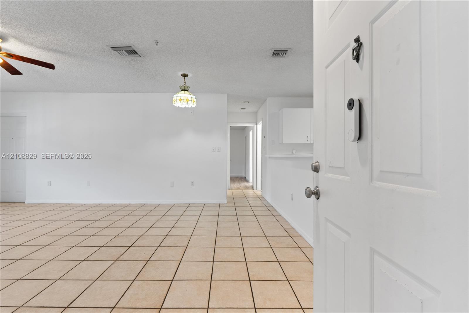 Interior featuring square ceramic floor tiling, ceiling fan with light kit, pendant lighting, and neutral wall tones