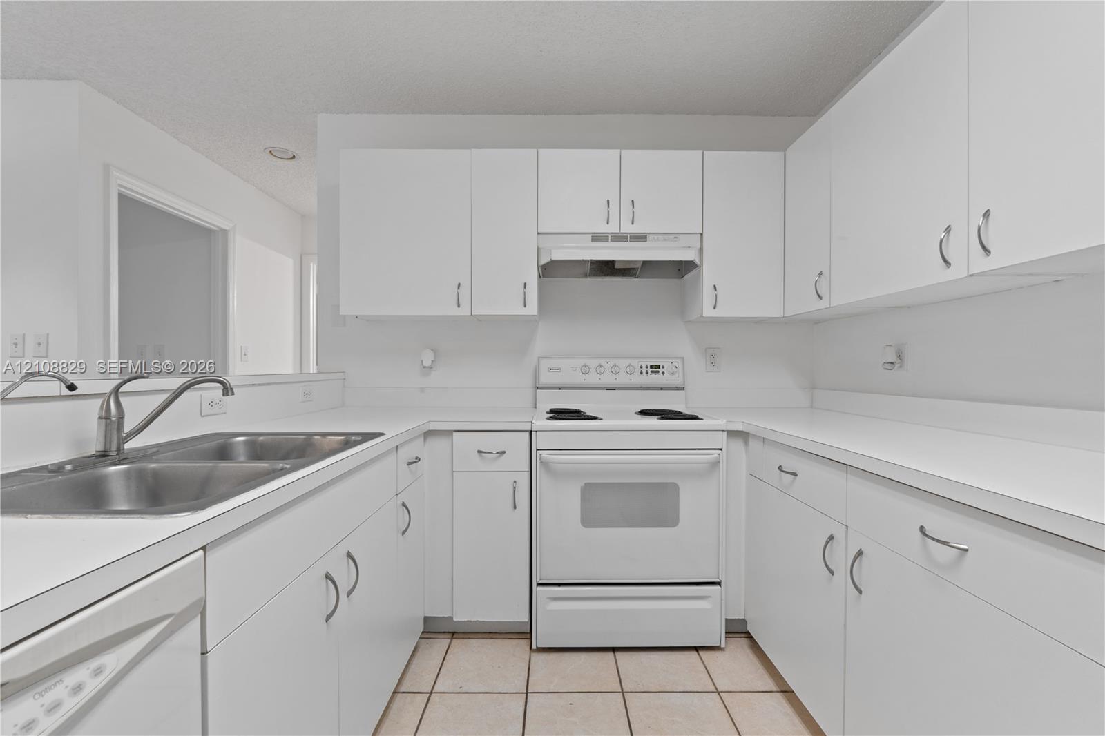 Kitchen featuring white cabinetry with silver-tone hardware, white countertops, integrated range hood, built-in electric range, and double-basin stainless steel sink with high-arc faucet
