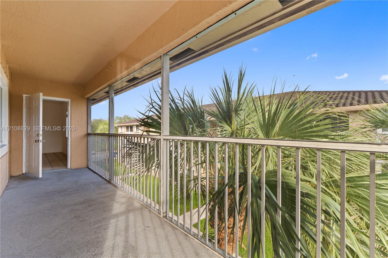 Screened balcony featuring concrete flooring, a metal railing, and a covered ceiling