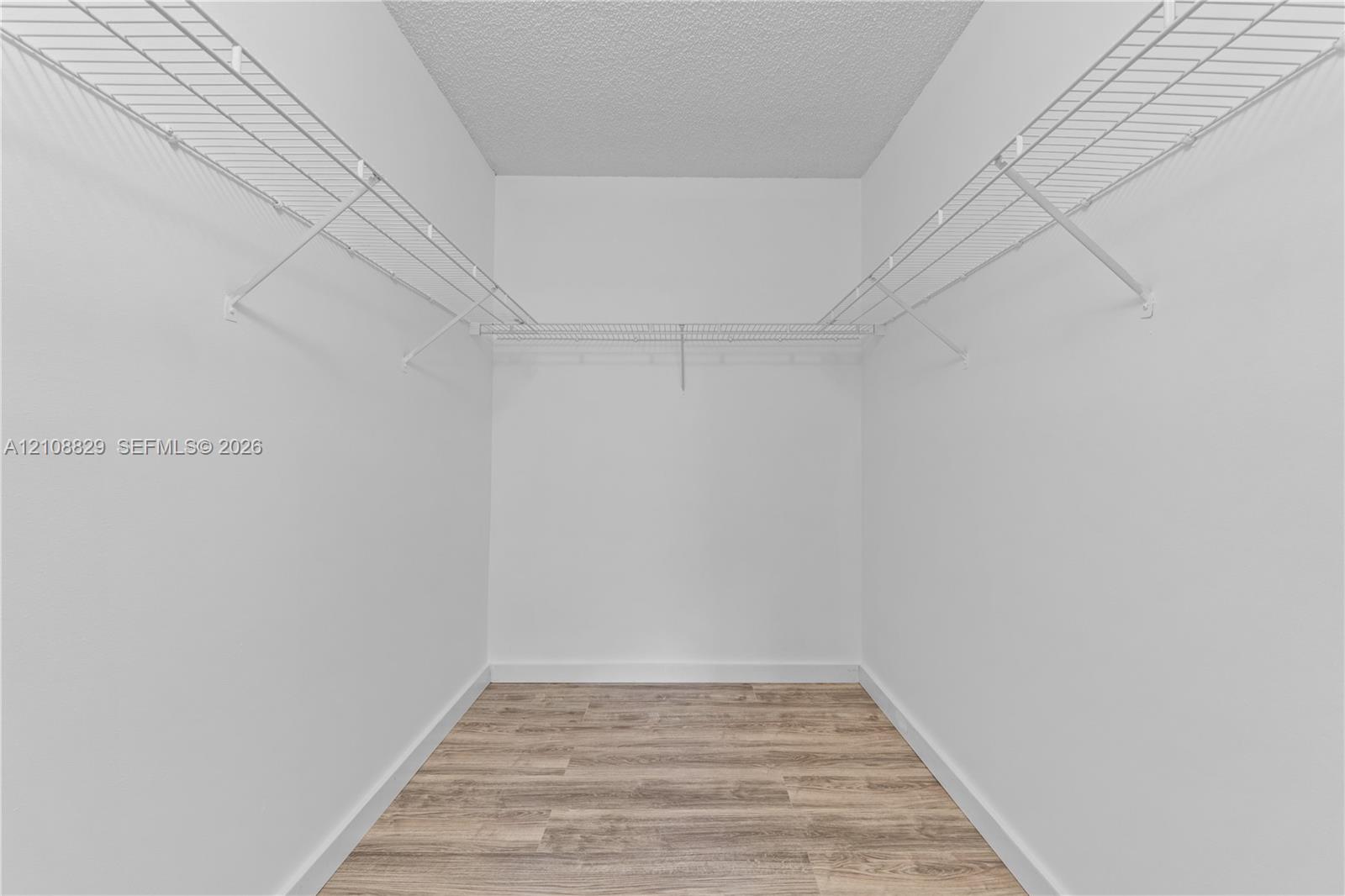 Walk-in closet featuring wood-finish flooring and tiered white wire shelving