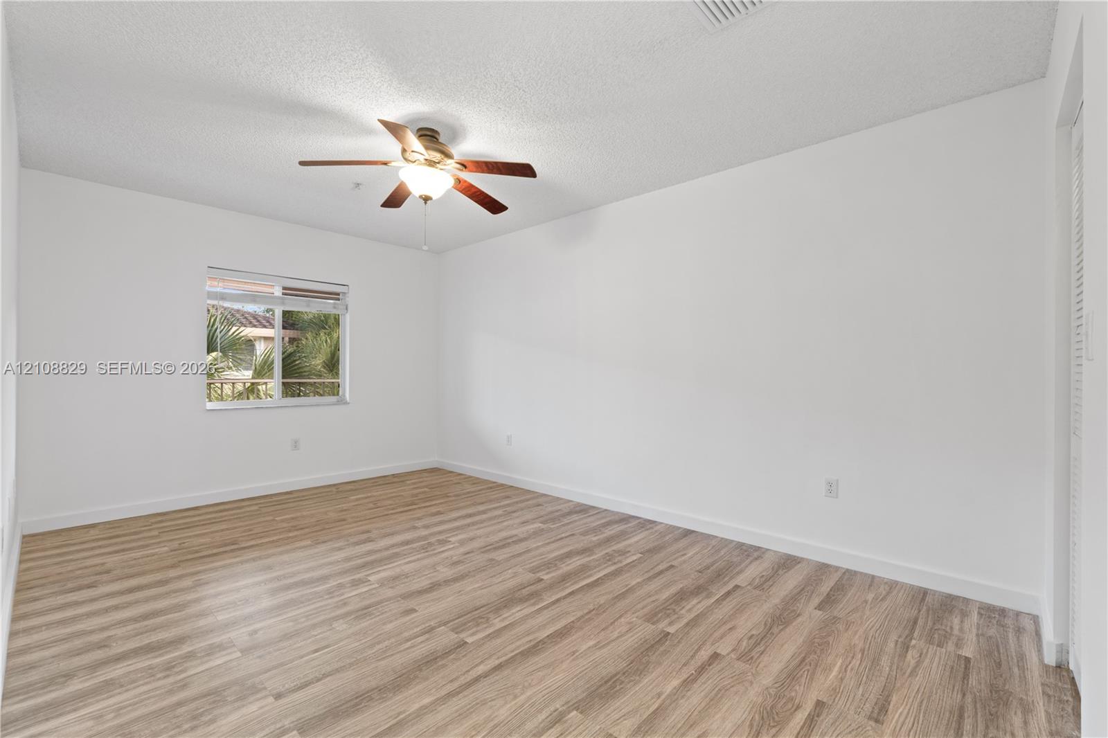 Interior room featuring wood-finish flooring, a ceiling fan with integrated lighting, and a single-pane window