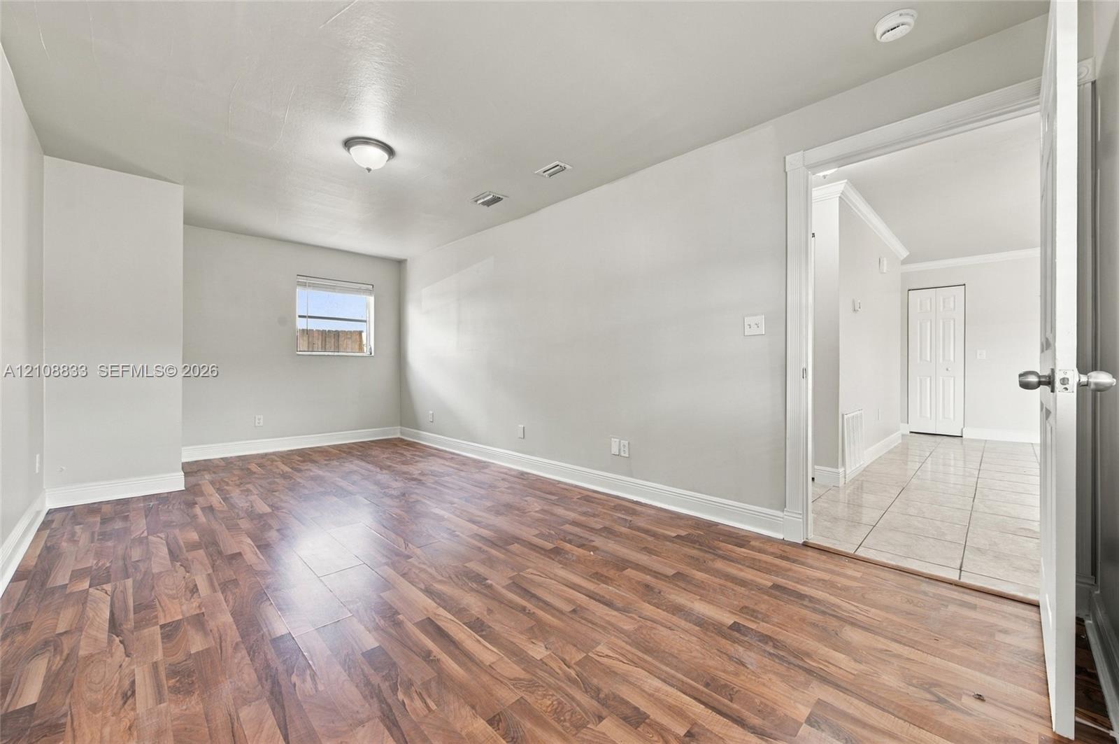 Interior room featuring wood-finish flooring, neutral wall paint, and a single-pane window
