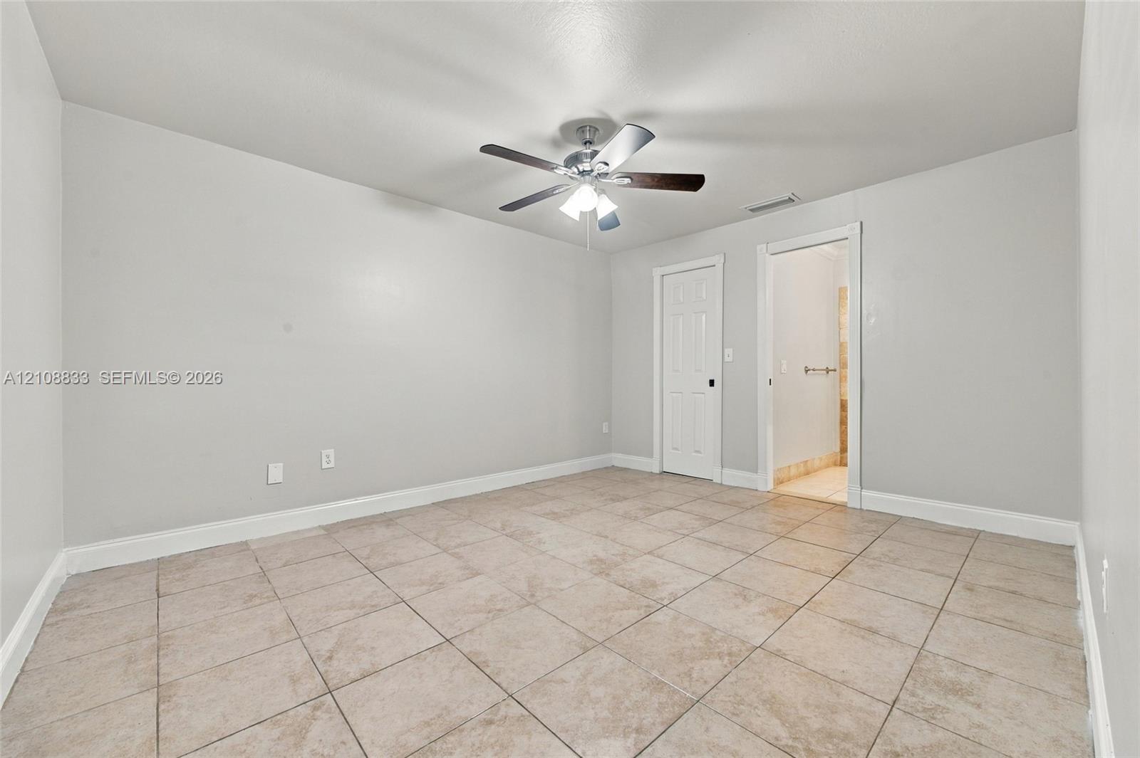 Room featuring large-format ceramic floor tile, neutral wall paint, and a ceiling-mounted light fixture with a multi-blade fan