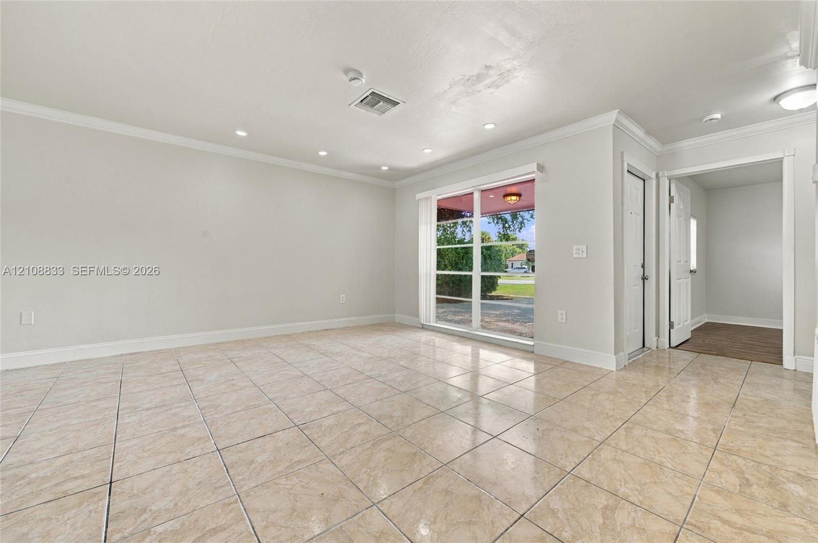 Interior space featuring large-format tile flooring, recessed lighting, crown molding, and expansive sliding glass doors