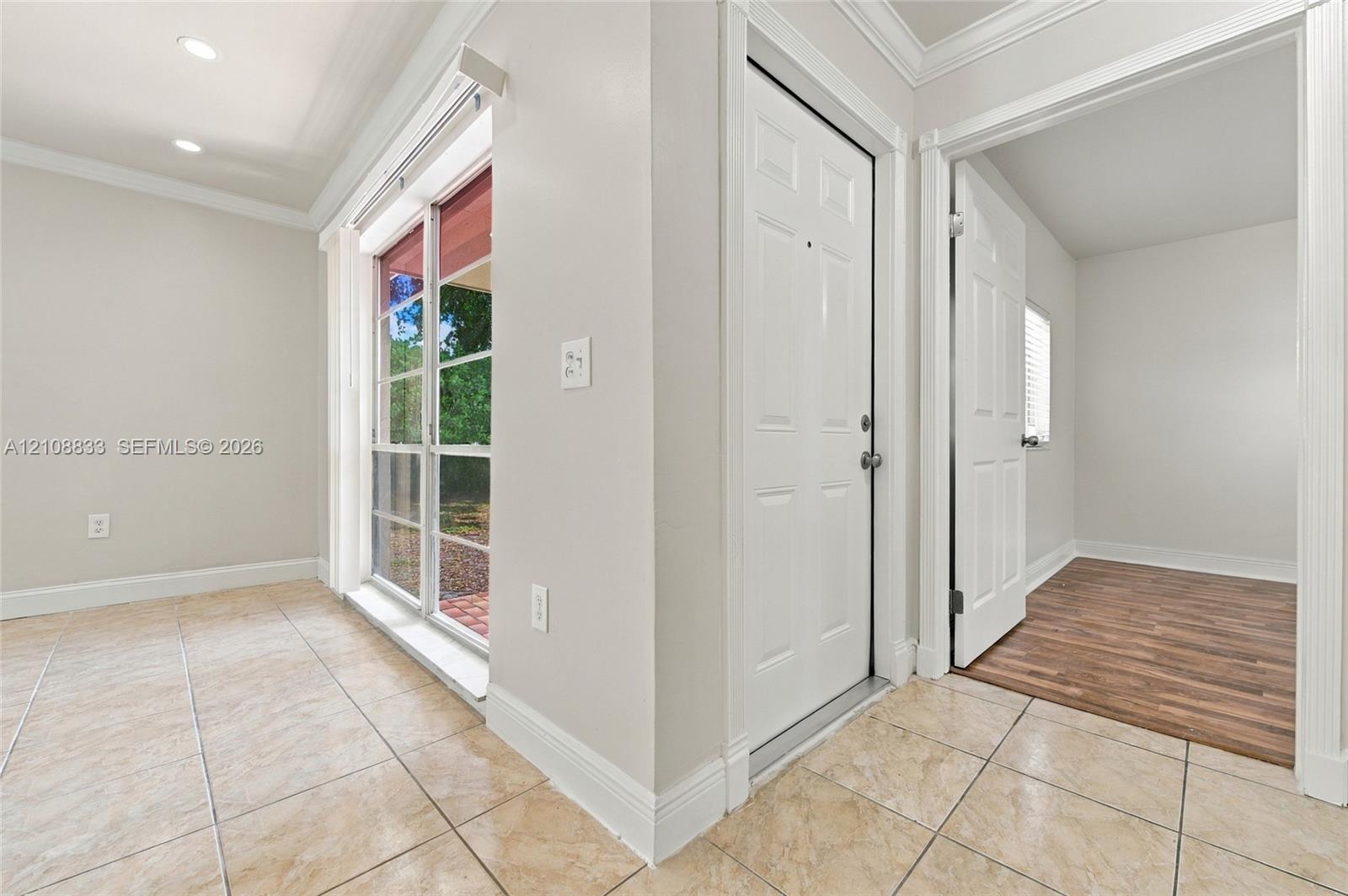 Interior space featuring ceramic tile flooring, recessed lighting, crown molding, sliding glass patio door, and wood-finish flooring