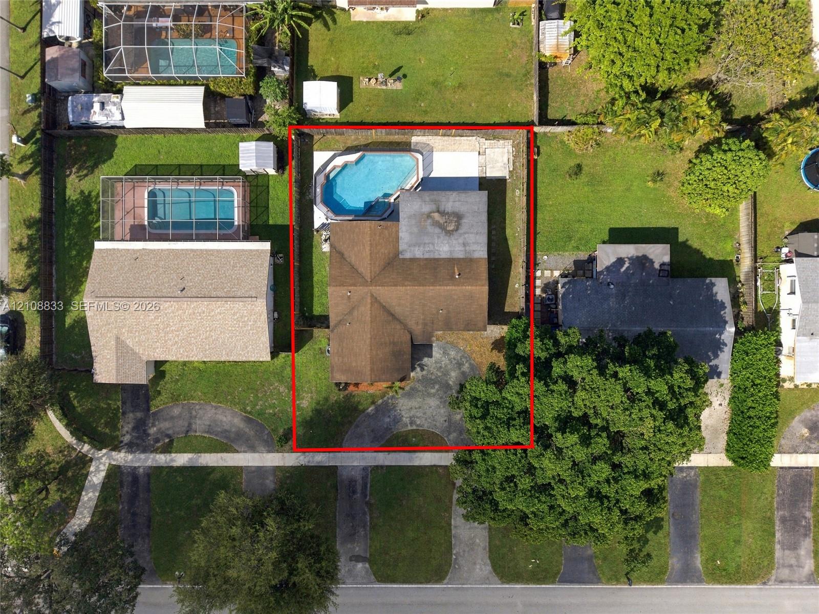 Aerial perspective featuring an asphalt driveway, a shingled roof, and a backyard swimming pool with a concrete deck