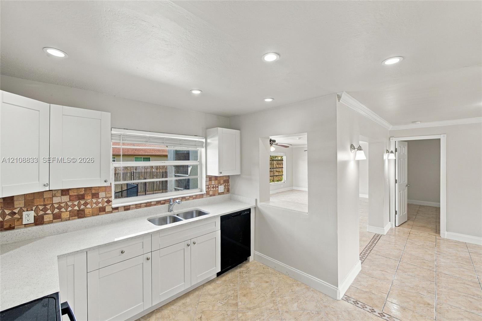 Kitchen featuring white cabinetry, solid-surface countertops, mosaic tile backsplash, recessed lighting, and tile flooring