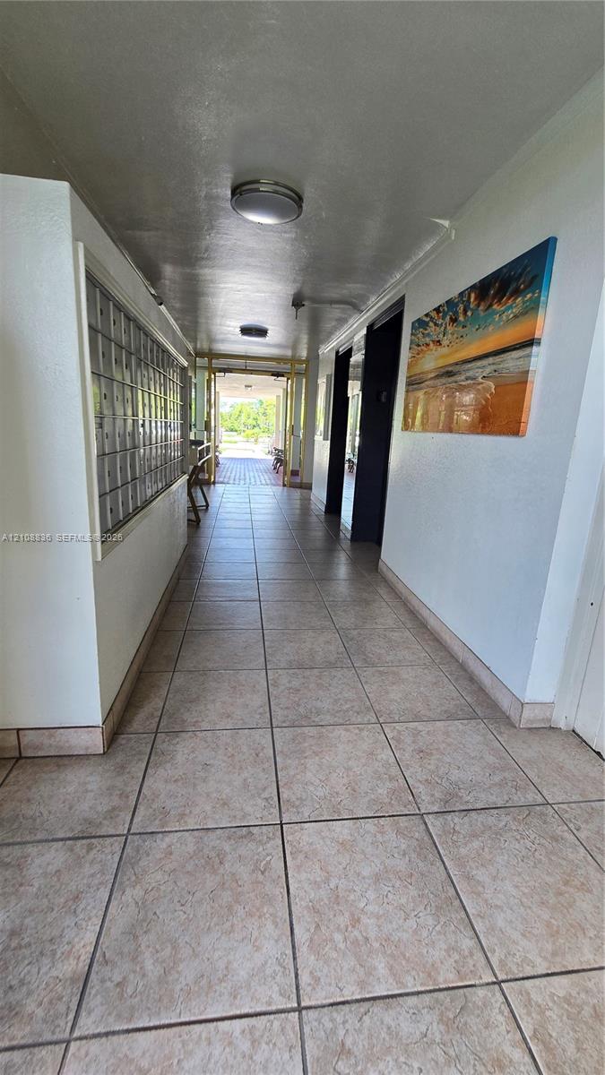 Interior hallway featuring ceramic tile flooring, flush-mount ceiling lighting, and built-in wall-mounted mailboxes