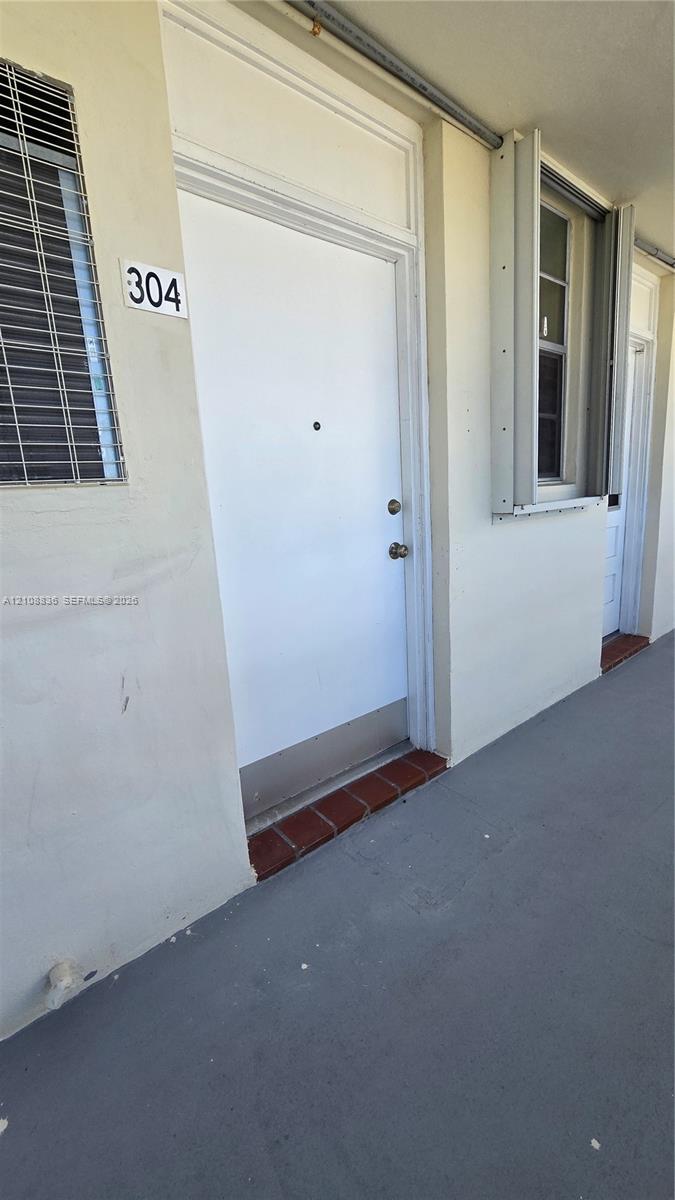 Exterior entry featuring a solid white door with a metal kickplate, transom window, and a red brick threshold