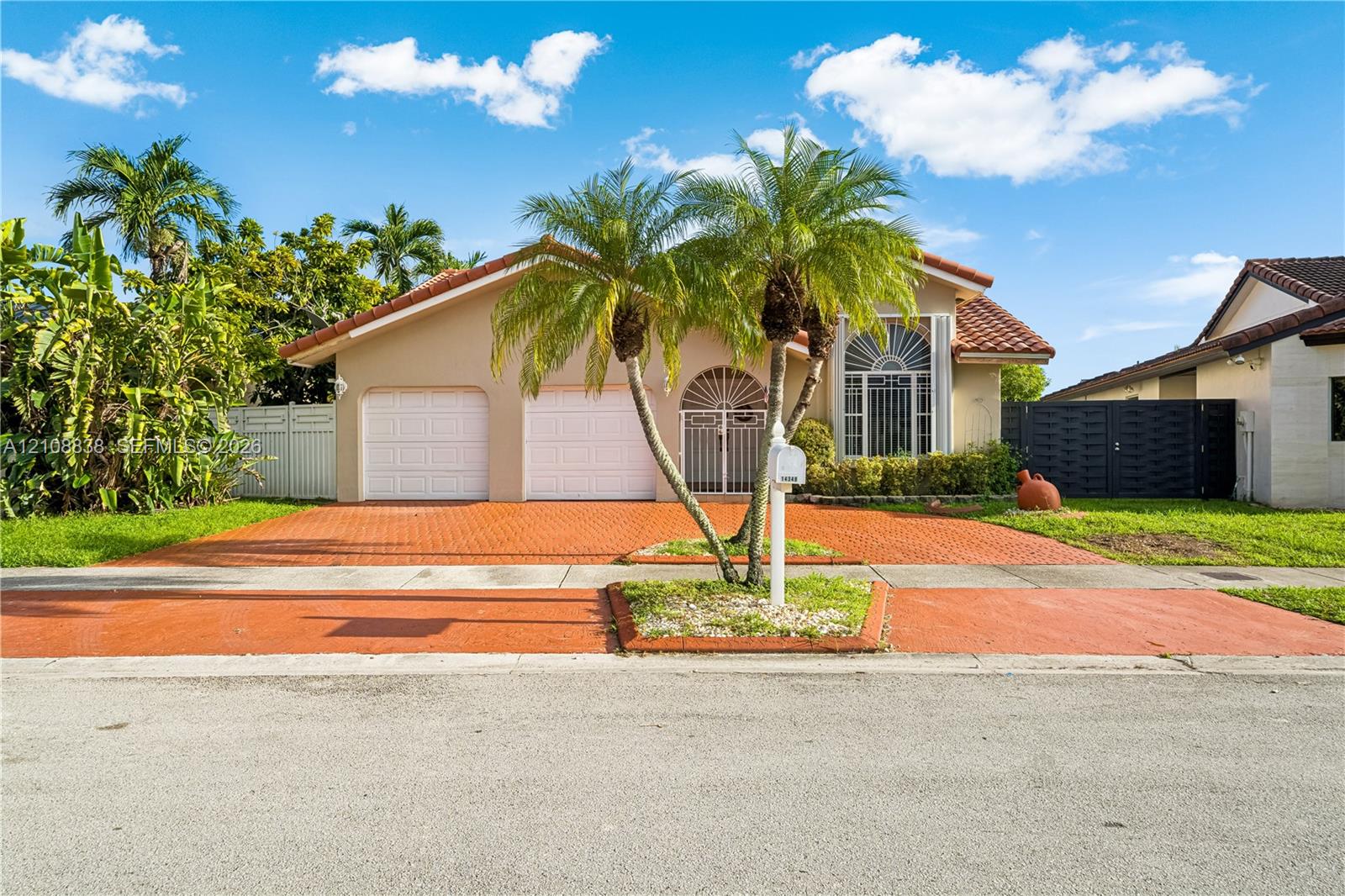 Exterior featuring a tile roof, stucco facade, decorative arched window detailing, two-car garage, and a stamped concrete driveway