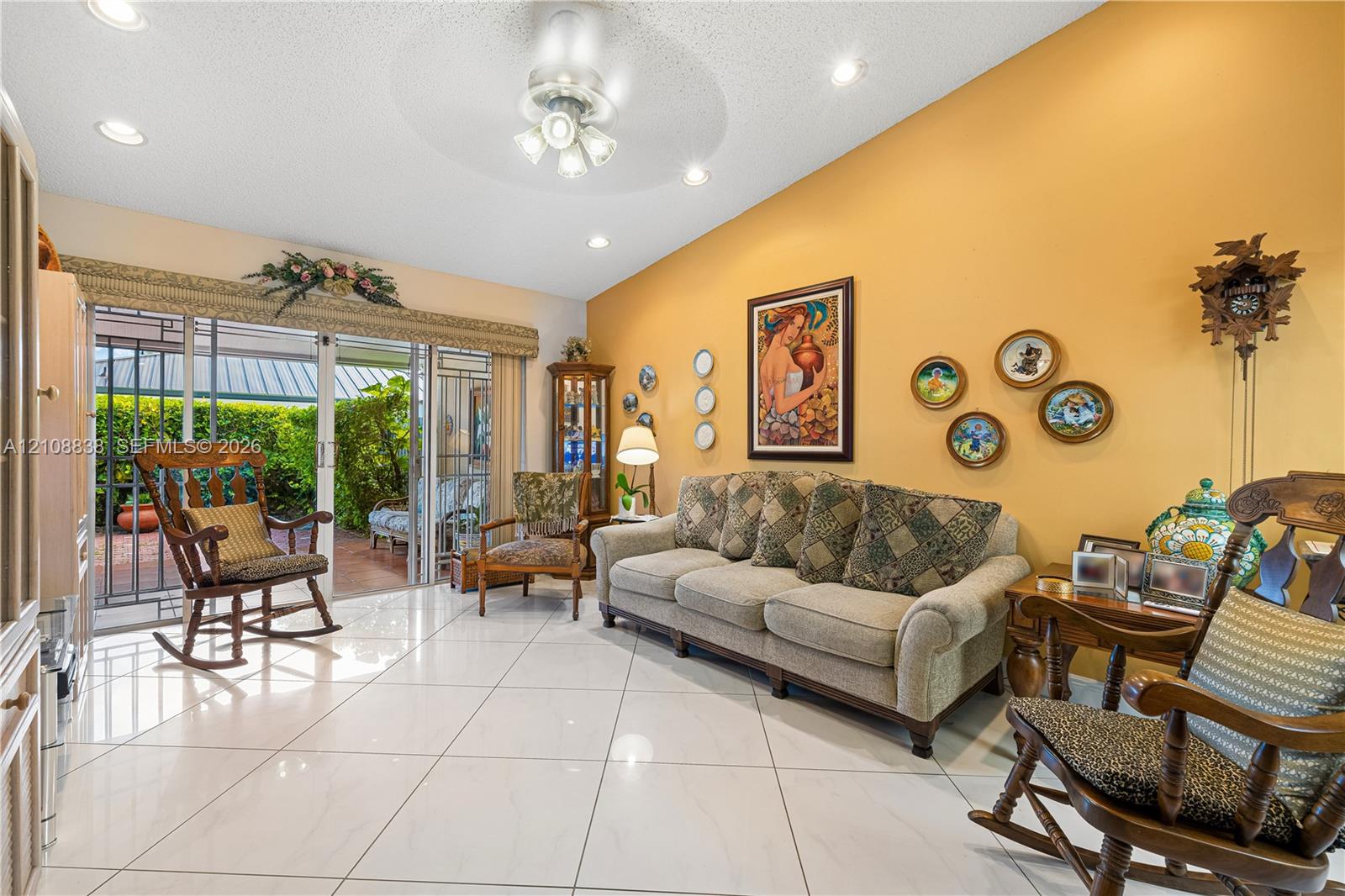 Vaulted ceilings, large-format tile flooring, recessed lighting, ceiling fan with integrated lighting, and sliding glass doors leading to a covered patio