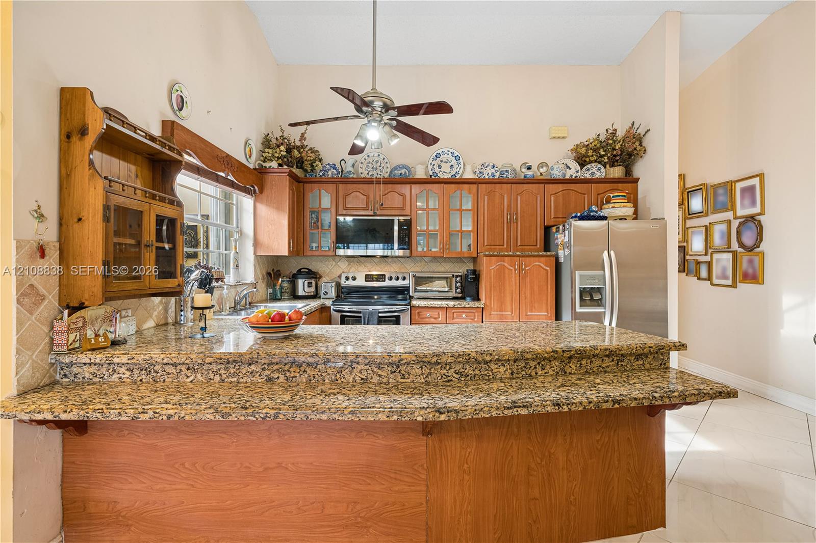Kitchen featuring raised-panel wood cabinetry, stone countertops, stainless steel appliances, a high ceiling, and tile flooring